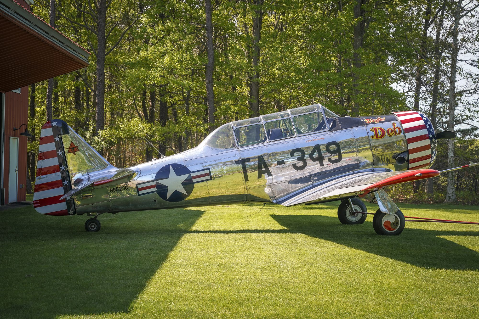 Polished silver T-6 Texan warbird parked on the grass